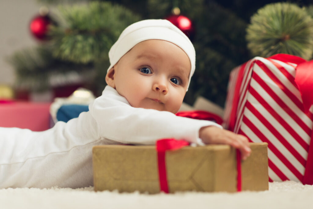 Bébé qui découvre son cadeau de Noël au pied du sapin
