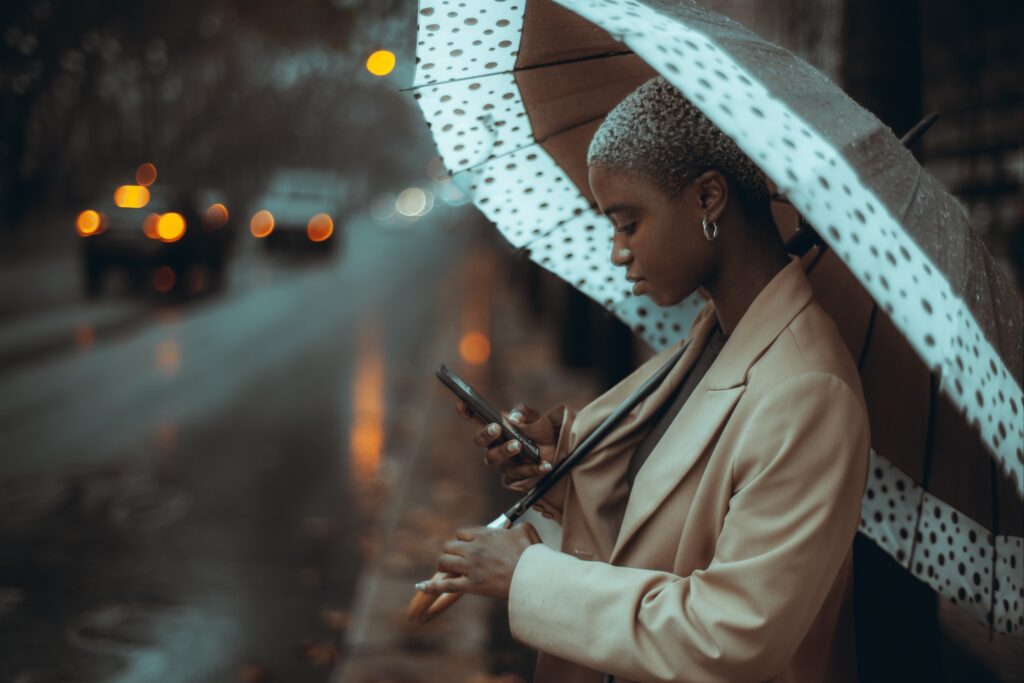 Femme d'affaires utilisant un smartphone sous un parapluie de Cherbourg à pois