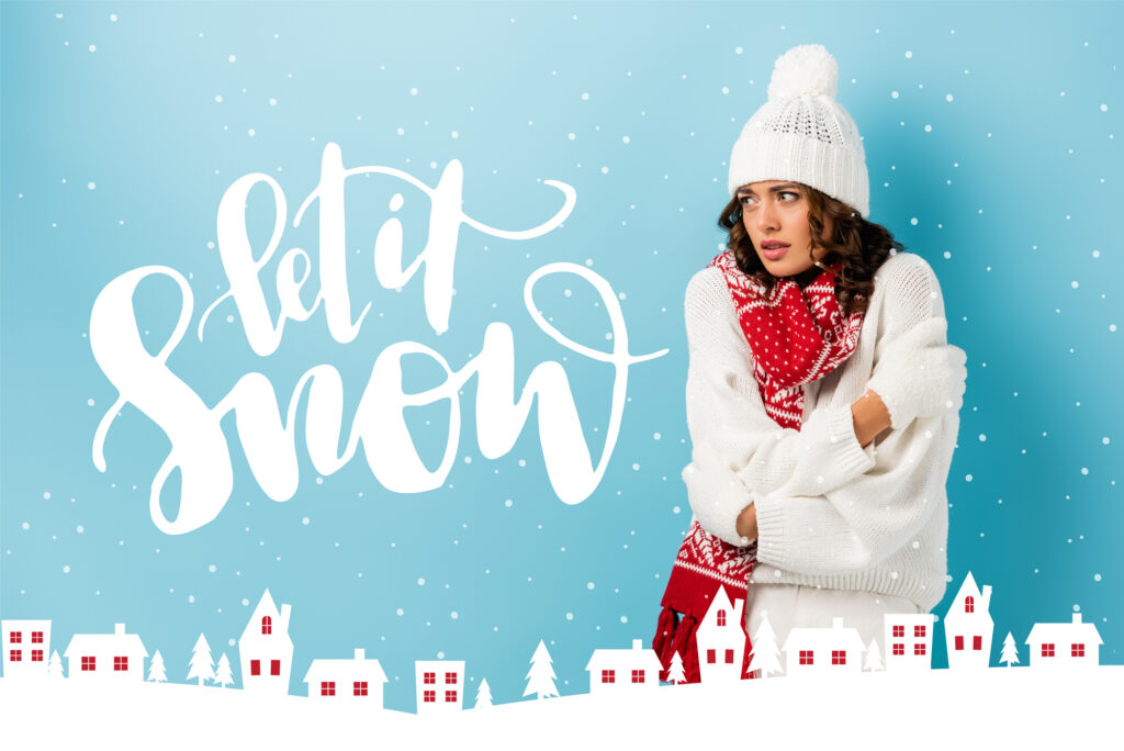 Femme en tenue d'hiver regardant au loin en écoutant la chanson Let it Snow et décorations de Noël