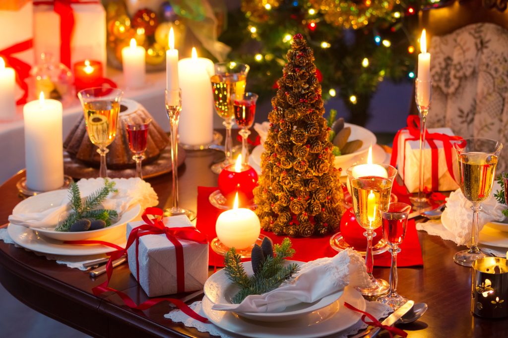 Table de Noël dressée : assiettes blanches, serviettes pliées, flûtes à champagne et sapin de pommes de pin