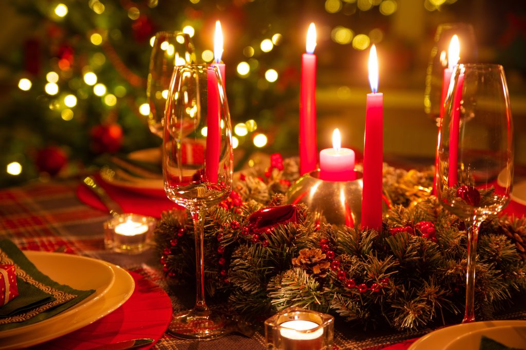 Centre de table de Noël avec couronne de sapin, bougies rouges allumées et flûtes à champagne