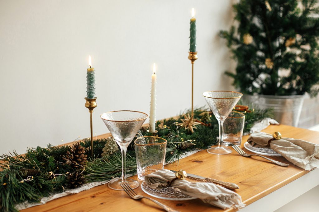 Chemin de table en branches de sapin et pommes de pin avec bougies vertes sur bougeoirs dorés