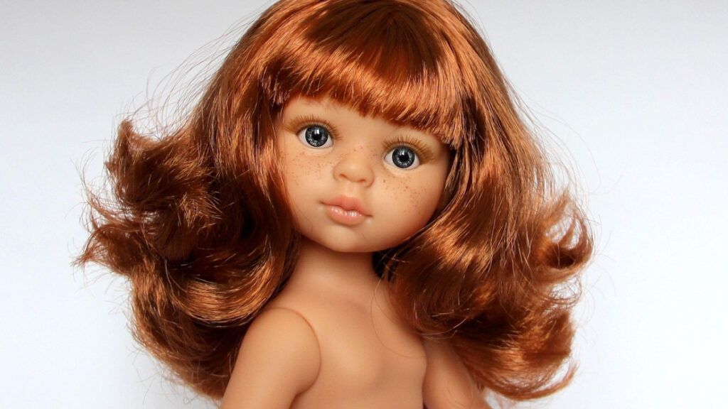 Poupée aux cheveux roux bouclés, frange et taches de rousseur, sur fond blanc