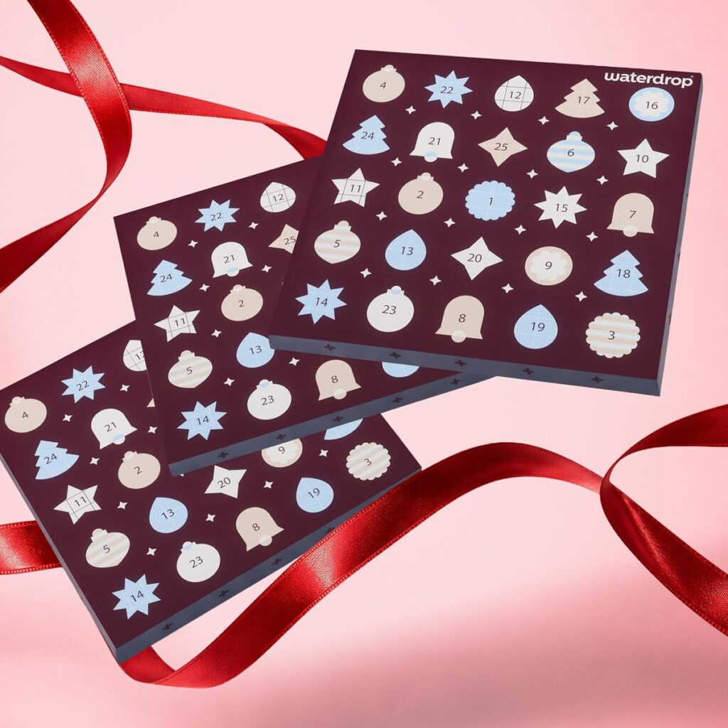 Trois calendriers de l’Avent waterdrop superposés avec un ruban rouge sur fond rose